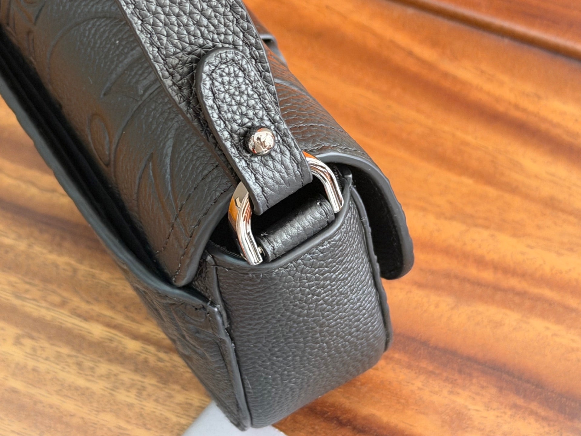 Dark leather Dior bag corner with embossed logo and metal snap hardware