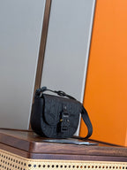 Small dark crossbody bag with flap closure and adjustable shoulder strap