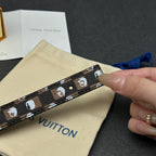 Louis Vuitton monogram strap close-up with white motifs, held over cream pouch