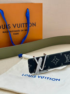 Louis Vuitton belt buckle close-up on dark navy monogram strap, gold-tone V.