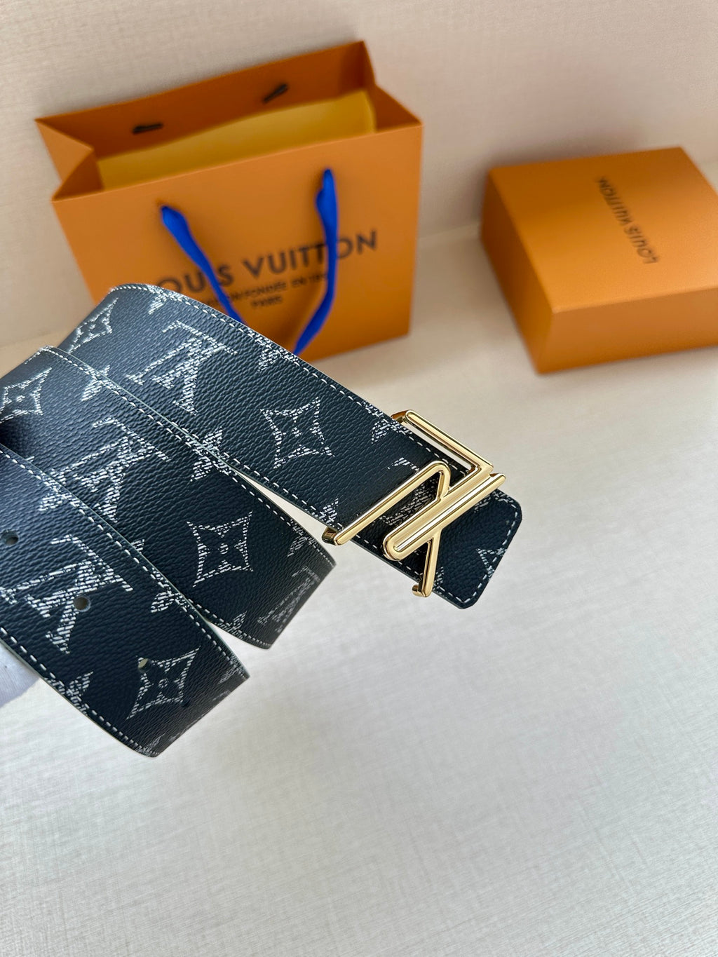 Louis Vuitton monogram belt with dark navy strap and gold-tone double-prong buckle.