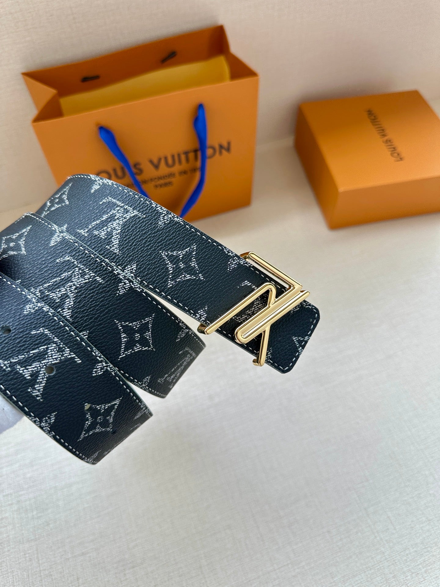 Louis Vuitton monogram belt with dark navy strap and gold-tone double-prong buckle.