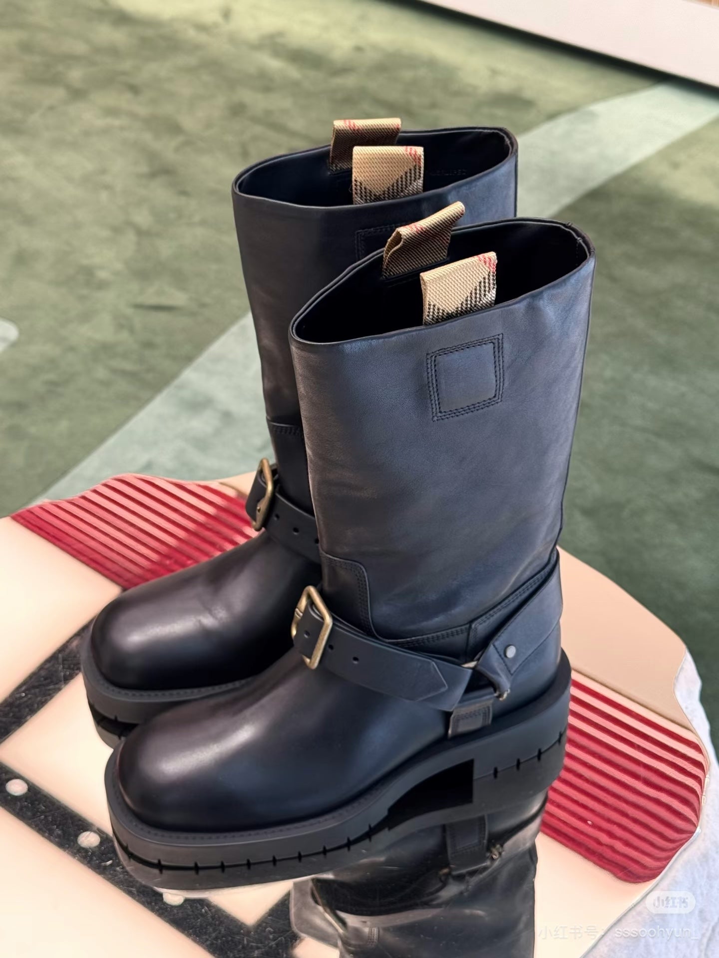 Dark navy leather mid-calf boots with buckled straps and thick sole.
