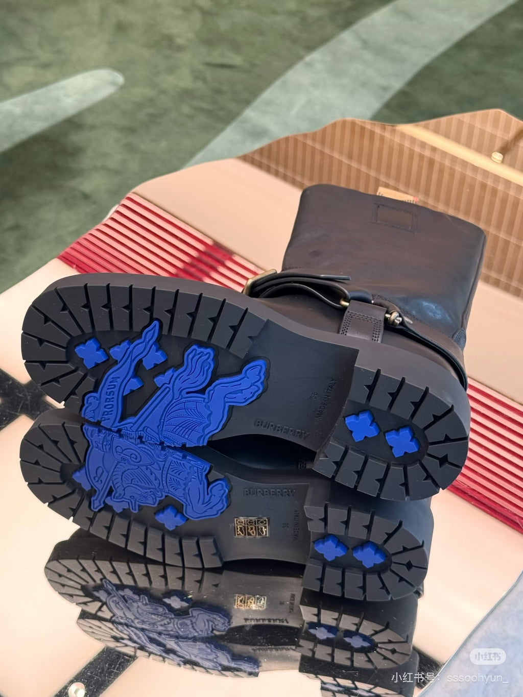 Boot outsoles with blue graphic tread and chunky rubber tread blocks.