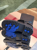 Boot outsoles with blue graphic tread and chunky rubber tread blocks.