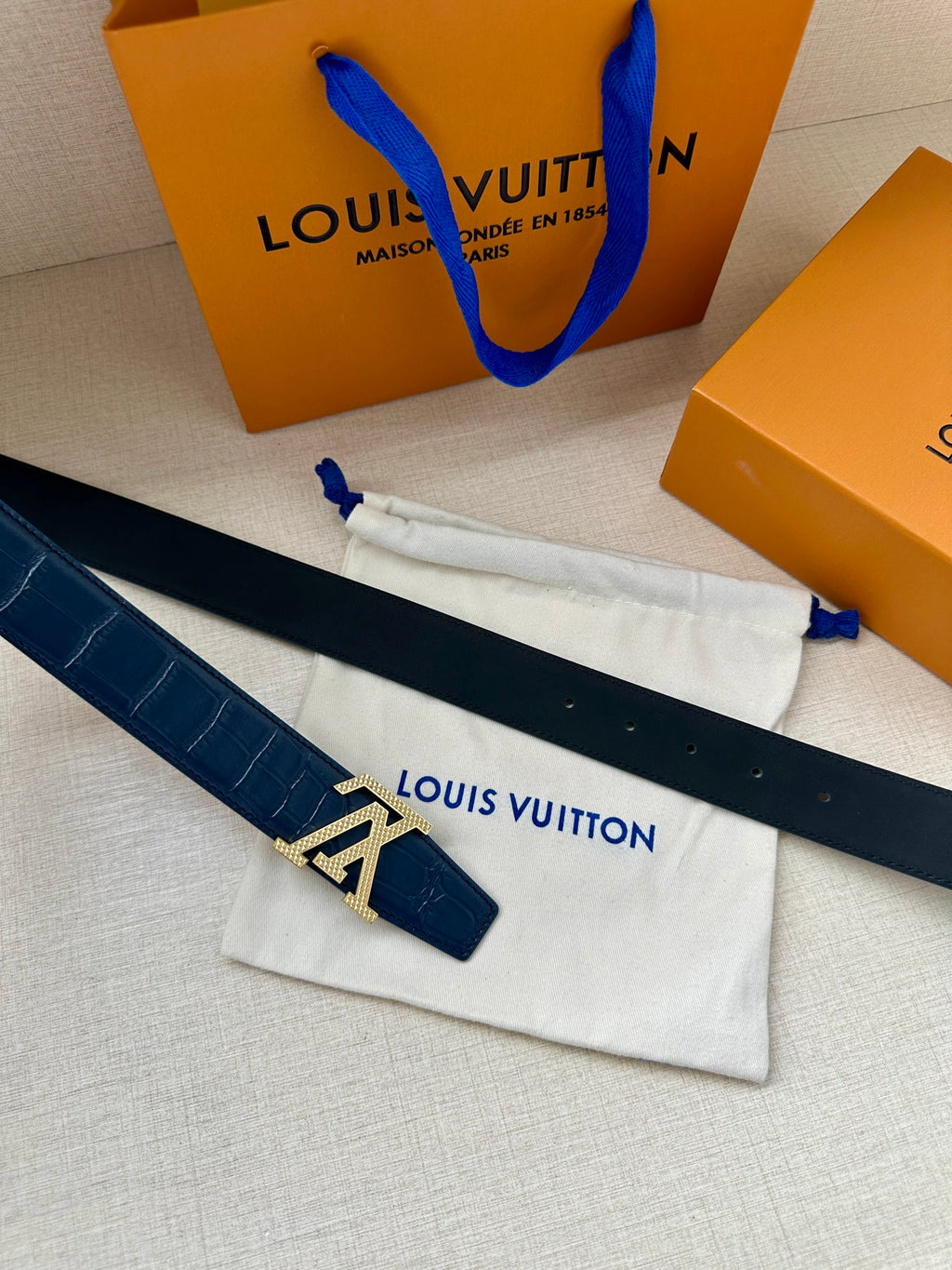 Louis Vuitton belt laid flat, dark blue embossed strap with silver LV buckle and prong