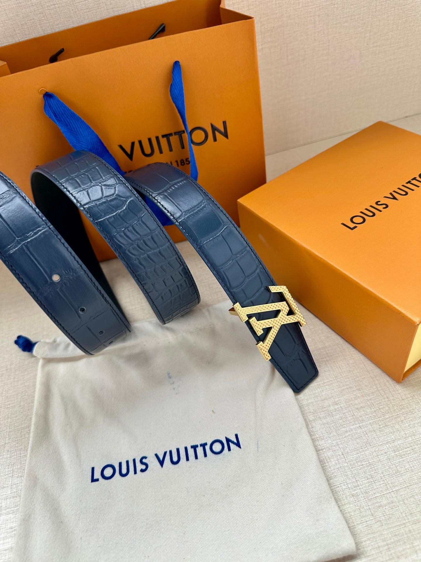 Louis Vuitton belt, dark blue embossed strap with large silver LV buckle and hole row