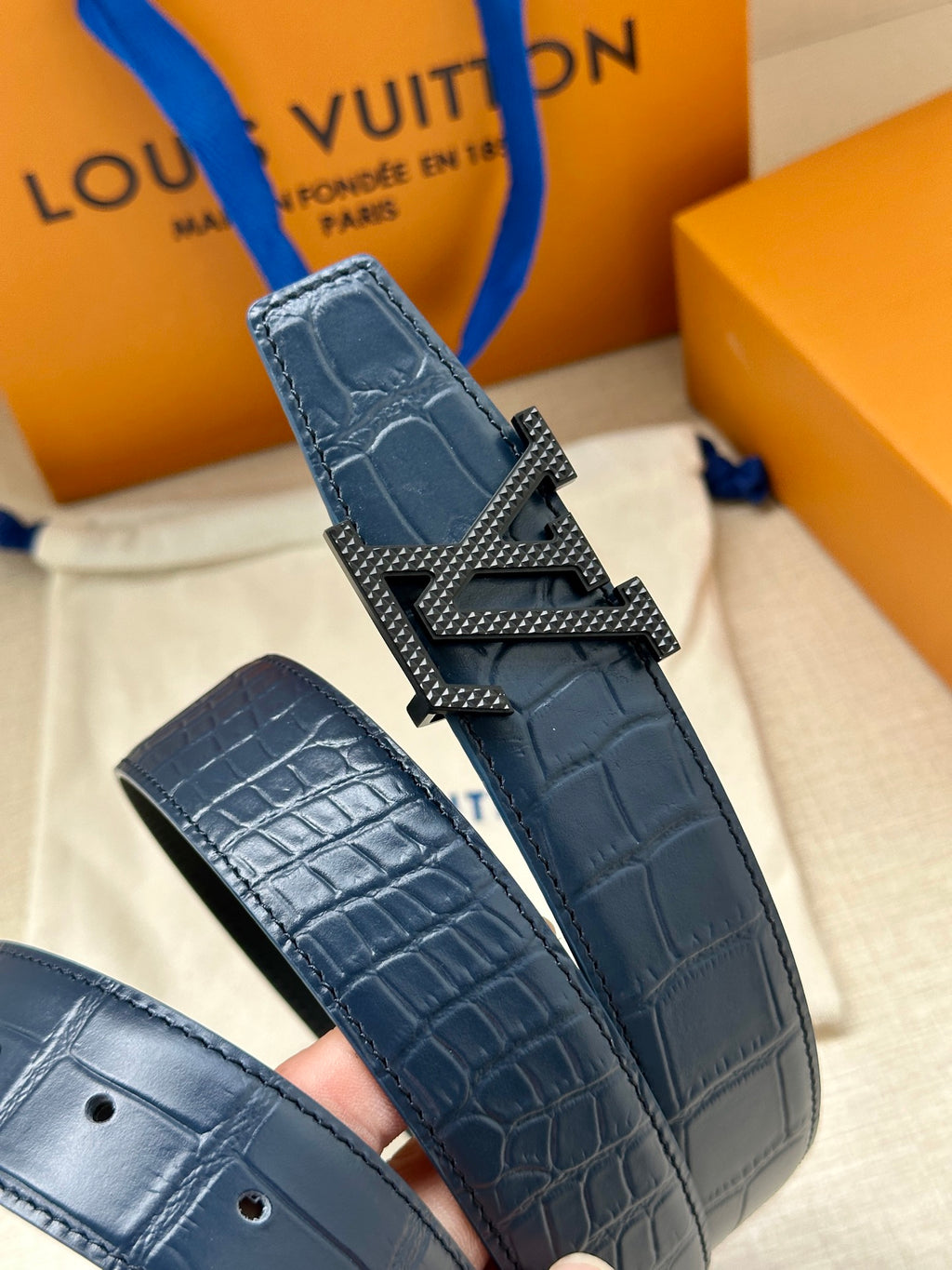 Louis Vuitton belt close-up, dark blue embossed leather with silver LV buckle