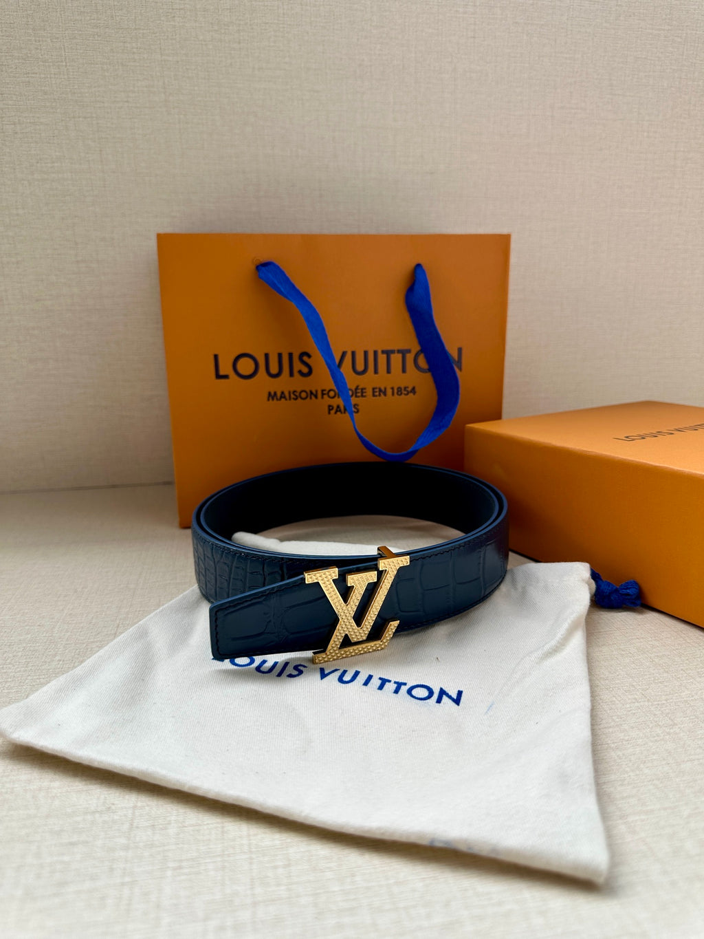 Louis Vuitton belt, dark blue leather strap with silver LV buckle shown with dust bag