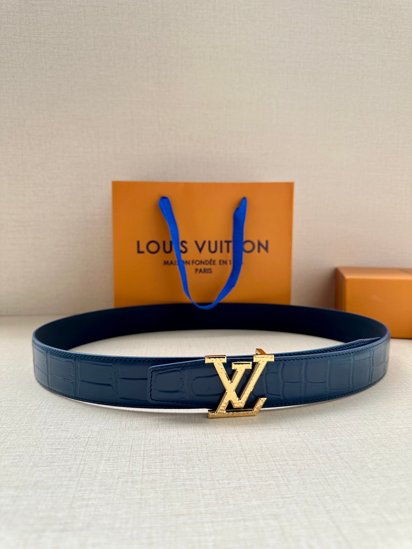 Blue leather belt with embossed texture and gold LV-style buckle