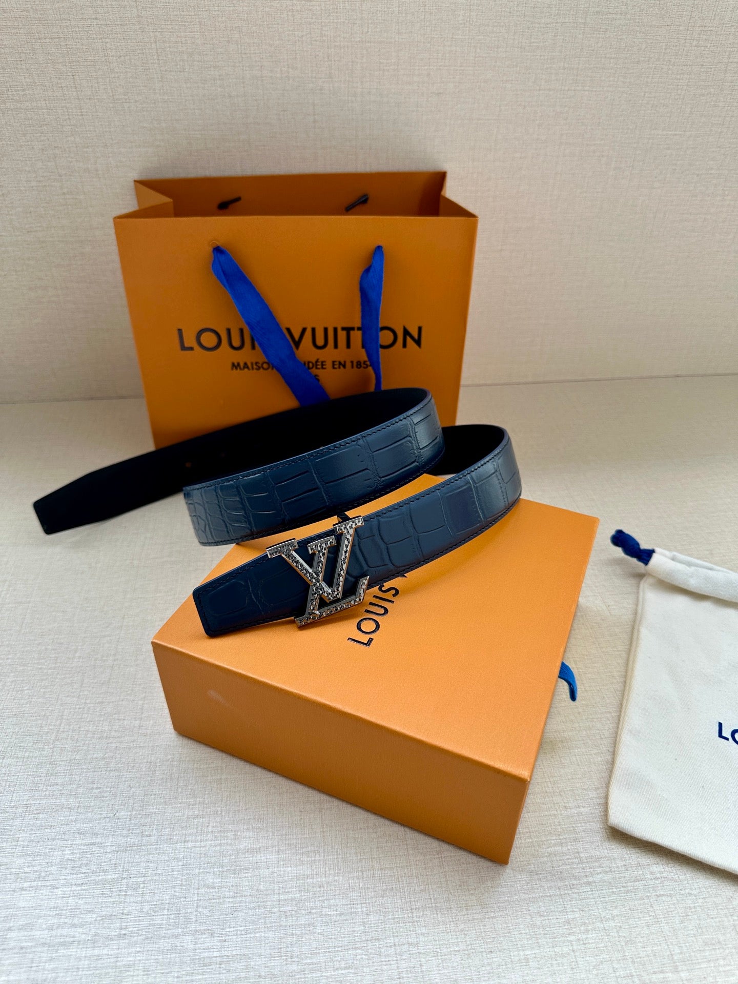 Blue leather belt with gold buckle, laid across the gift boxes
