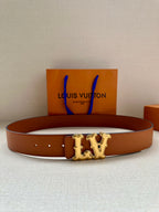 Tan leather belt with perforated strap and gold-toned LV buckle, with shopping bag in background
