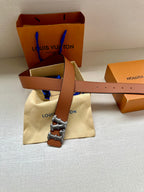 Tan leather belt with silver-toned LV buckle on a folded dust bag