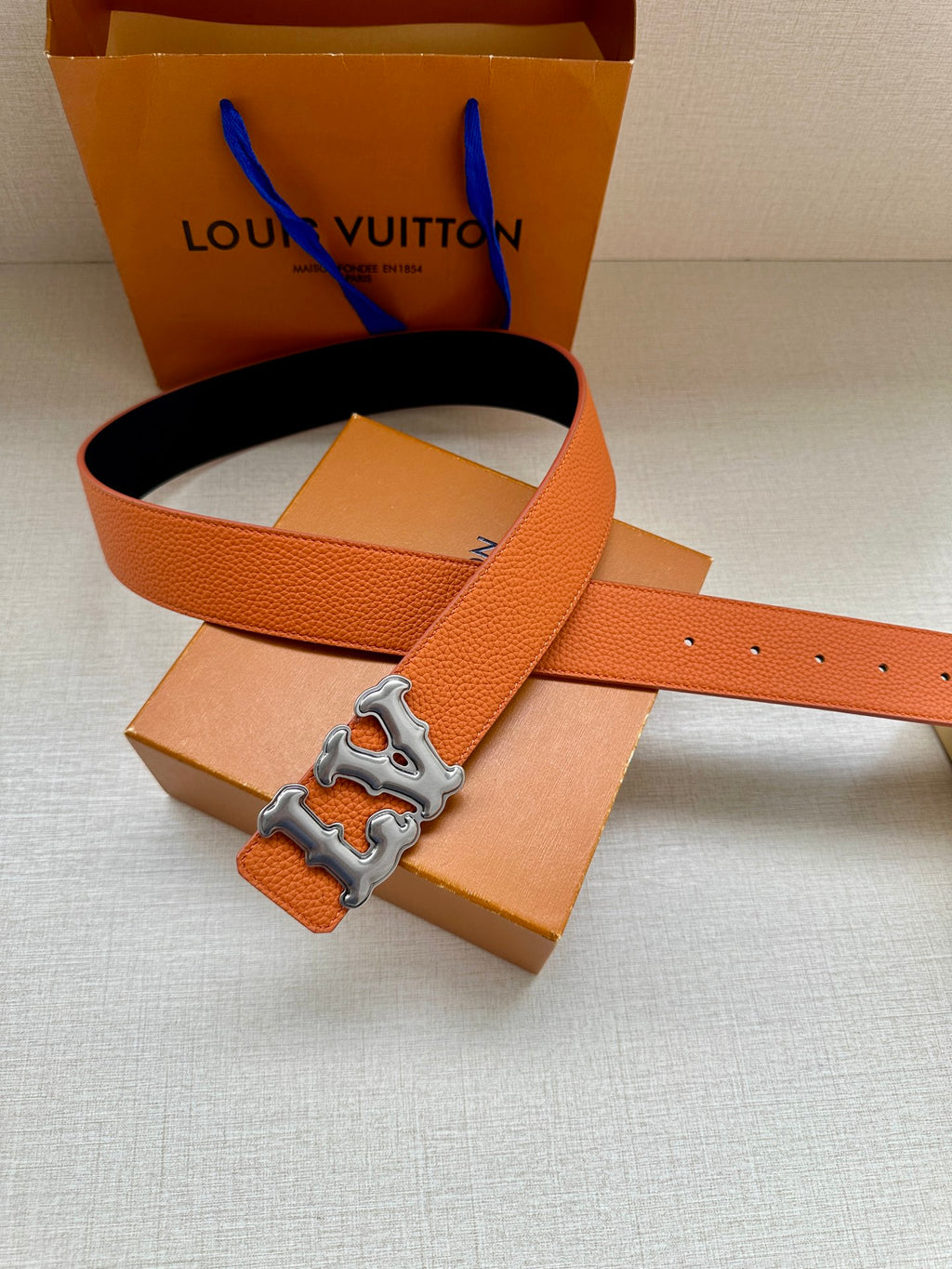 Orange leather belt with silver-tone LV buckle and dark navy strap end