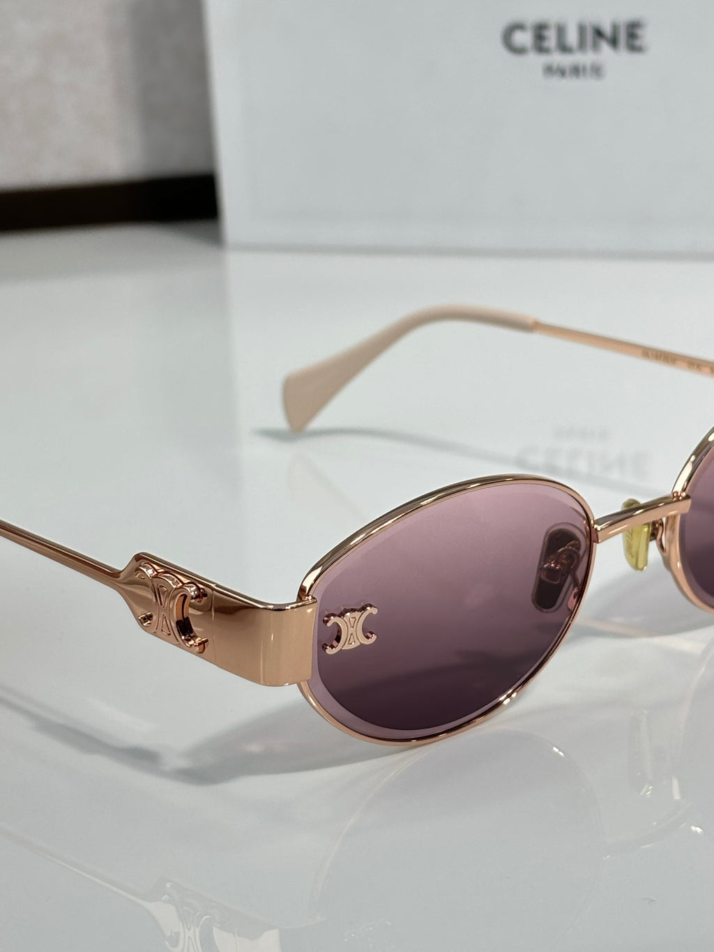 Oval sunglasses with rose gold frame and purple tinted lenses