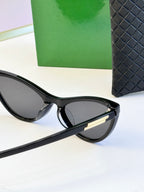 Black cat-eye sunglasses with dark lenses and gold-tone temple tips