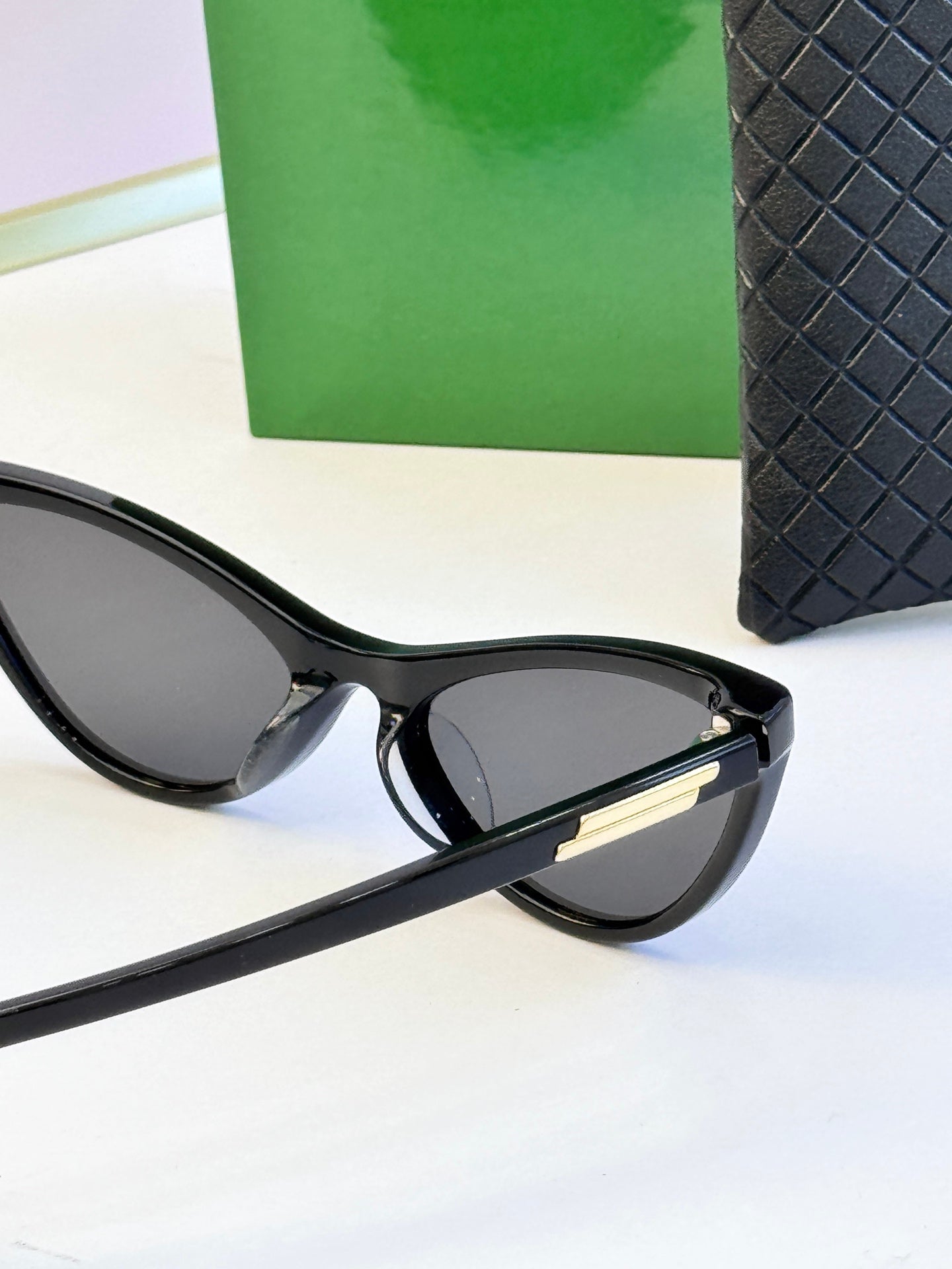 Black cat-eye sunglasses with dark lenses and gold-tone temple tips