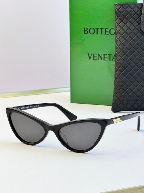 Black cat-eye sunglasses with dark lenses and gold-tone logo detail