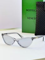 Clear cat-eye sunglasses with gray lenses and gold-tone temple detail