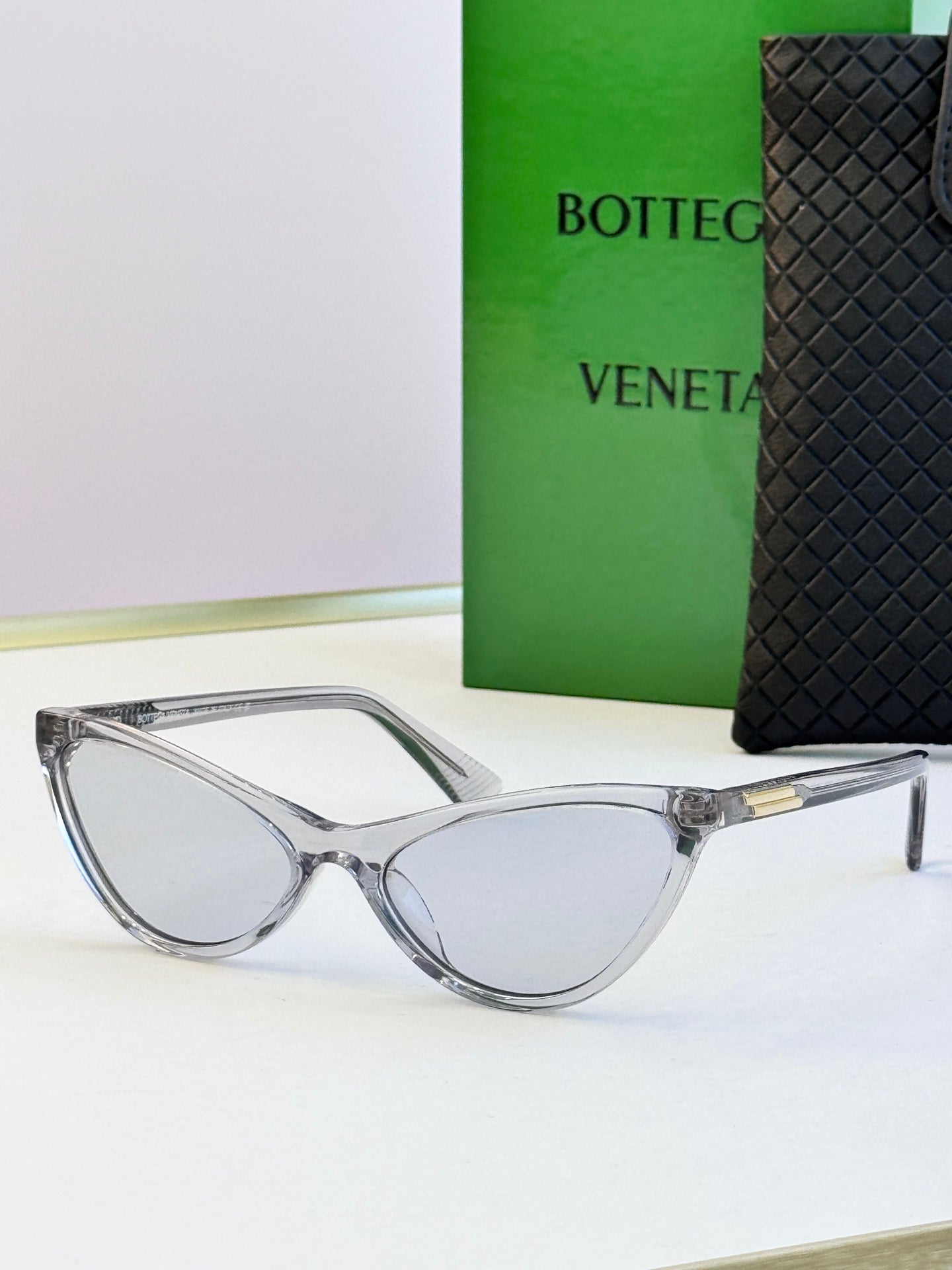 Clear cat-eye sunglasses with gray lenses and gold-tone temple detail