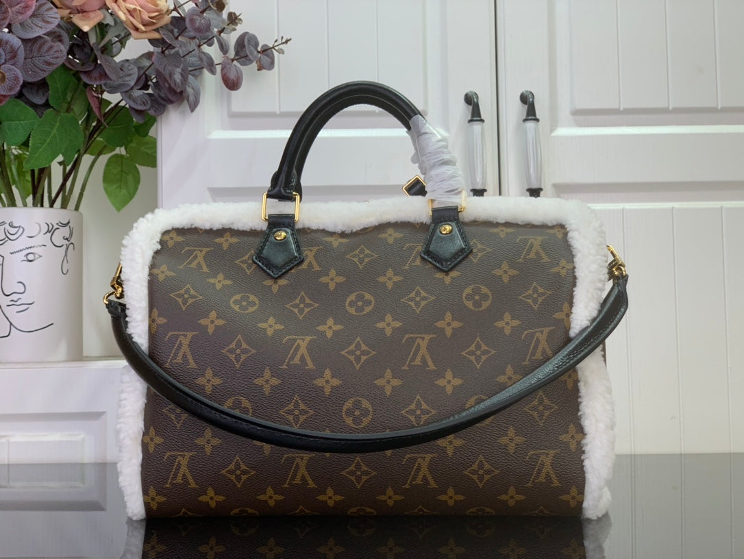 Monogram canvas handbag with curved top handles and white fuzzy trim, gold accents