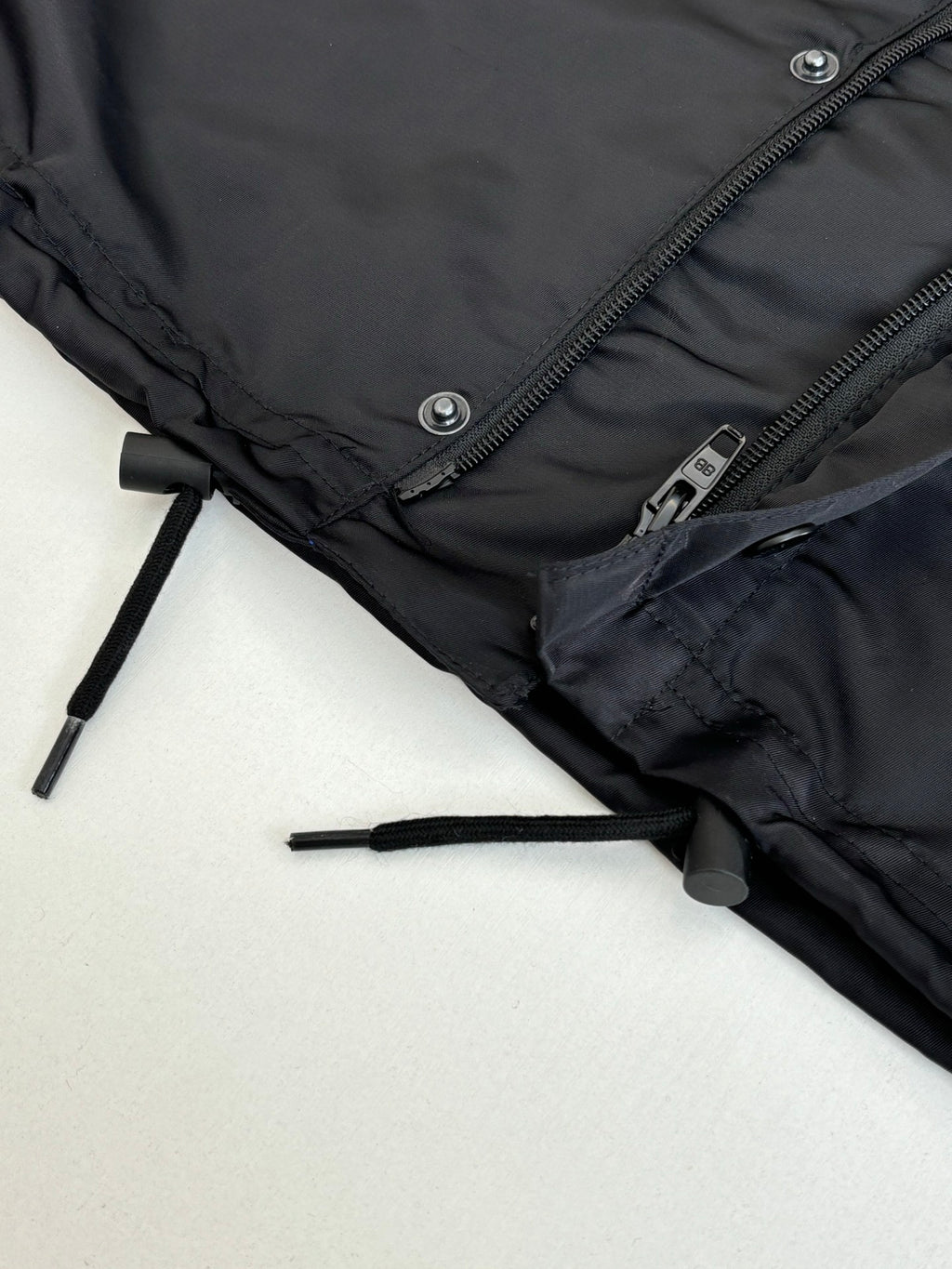 Black parka jacket hem close-up with drawcord toggle and zipper