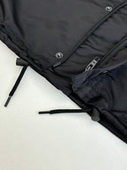 Black parka jacket hem close-up with drawcord toggle and zipper