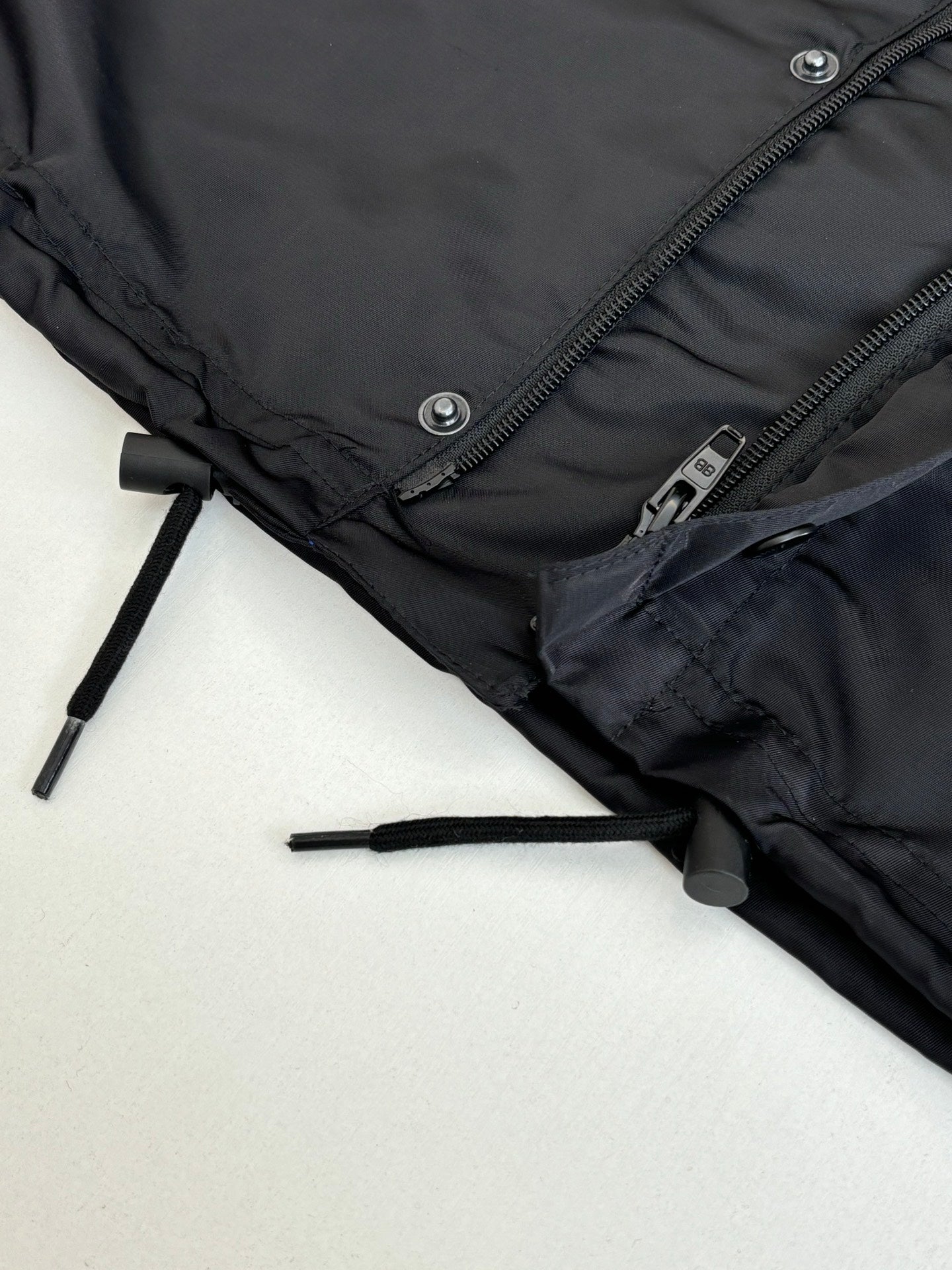 Black parka jacket hem close-up with drawcord toggle and zipper
