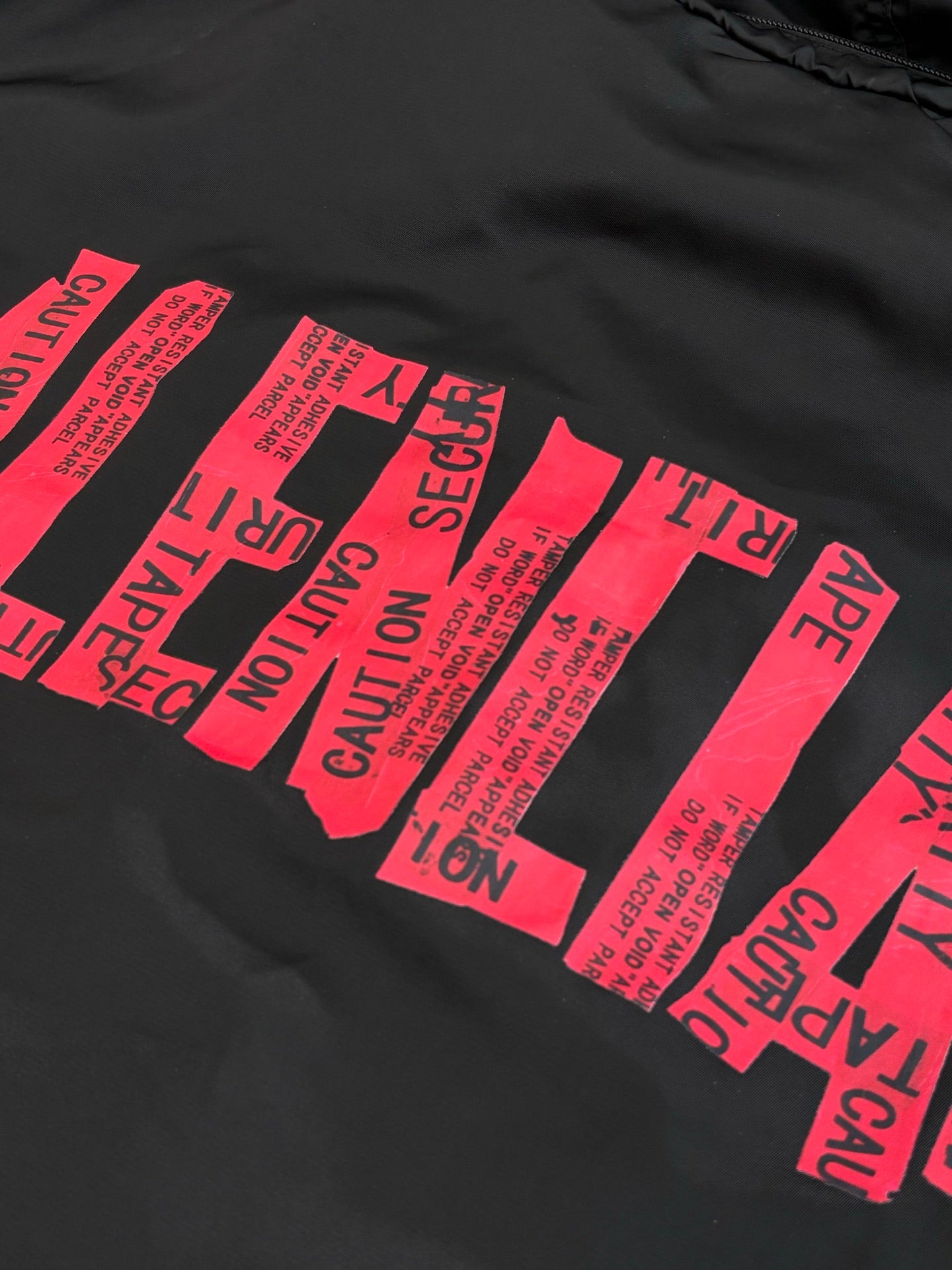 Black jacket fabric with bold pink typographic graphic print