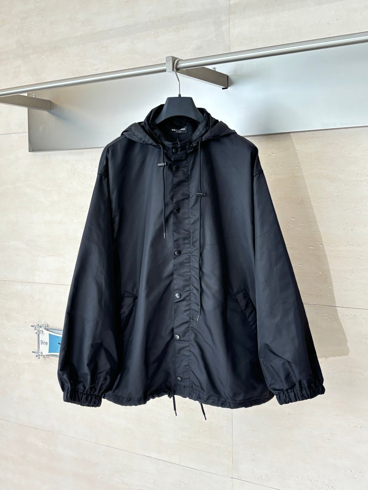 Black long hooded jacket with front snap placket and drawstring hem