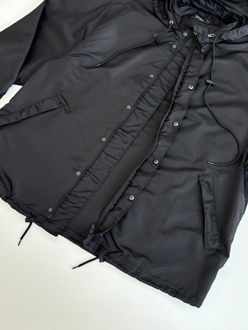Black parka jacket with drawstring hood and buttoned front placket