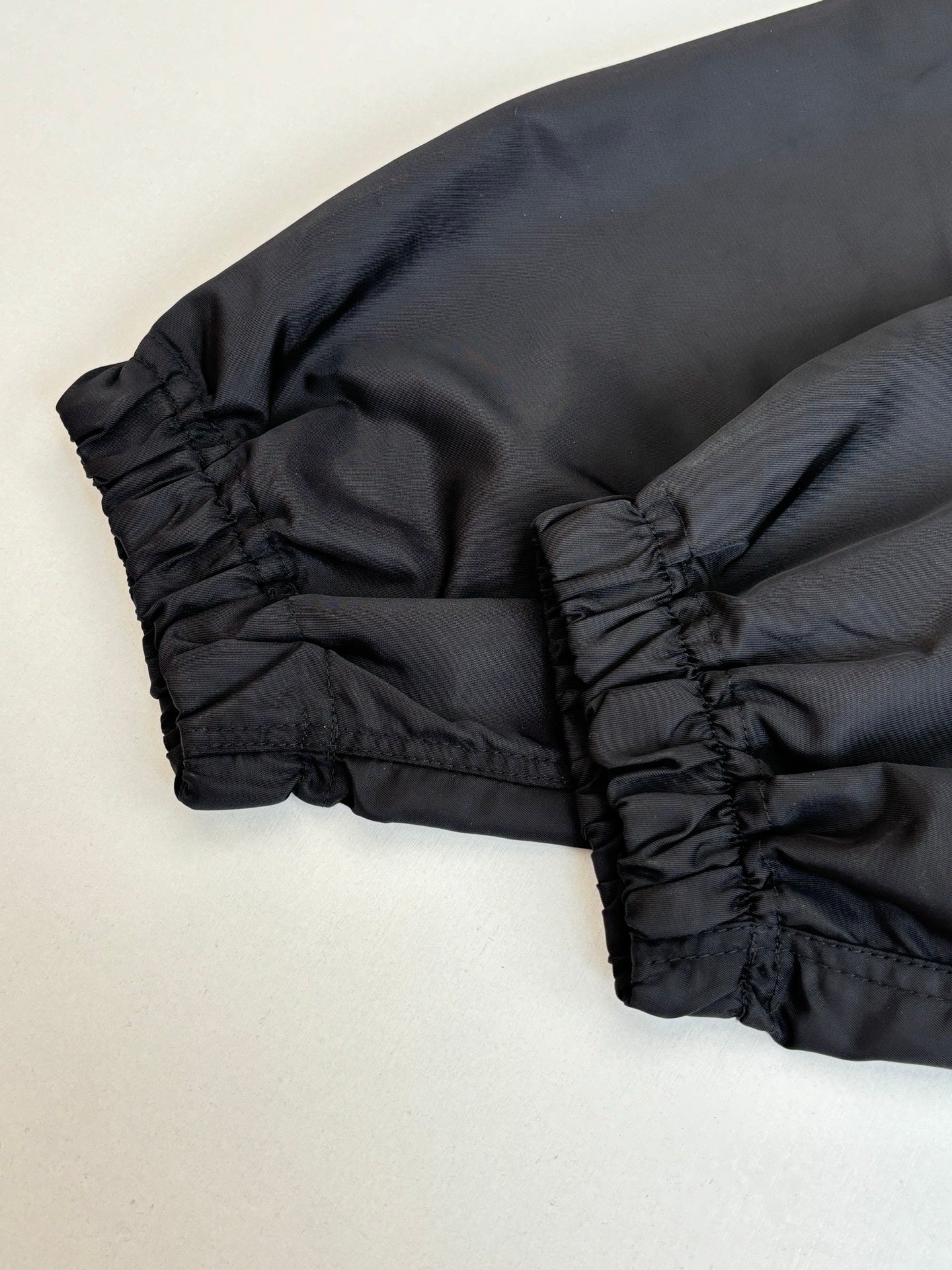 Black parka jacket hem and cuff detail with gathered stitching