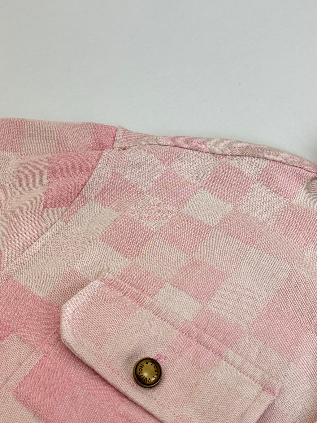 Pink check-pattern jacket hood edge with gold button detail