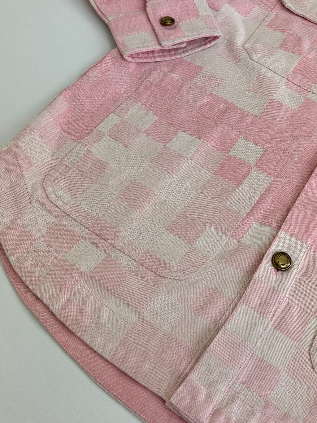Pink hooded jacket yoke area with check pattern, top button, and front pocket