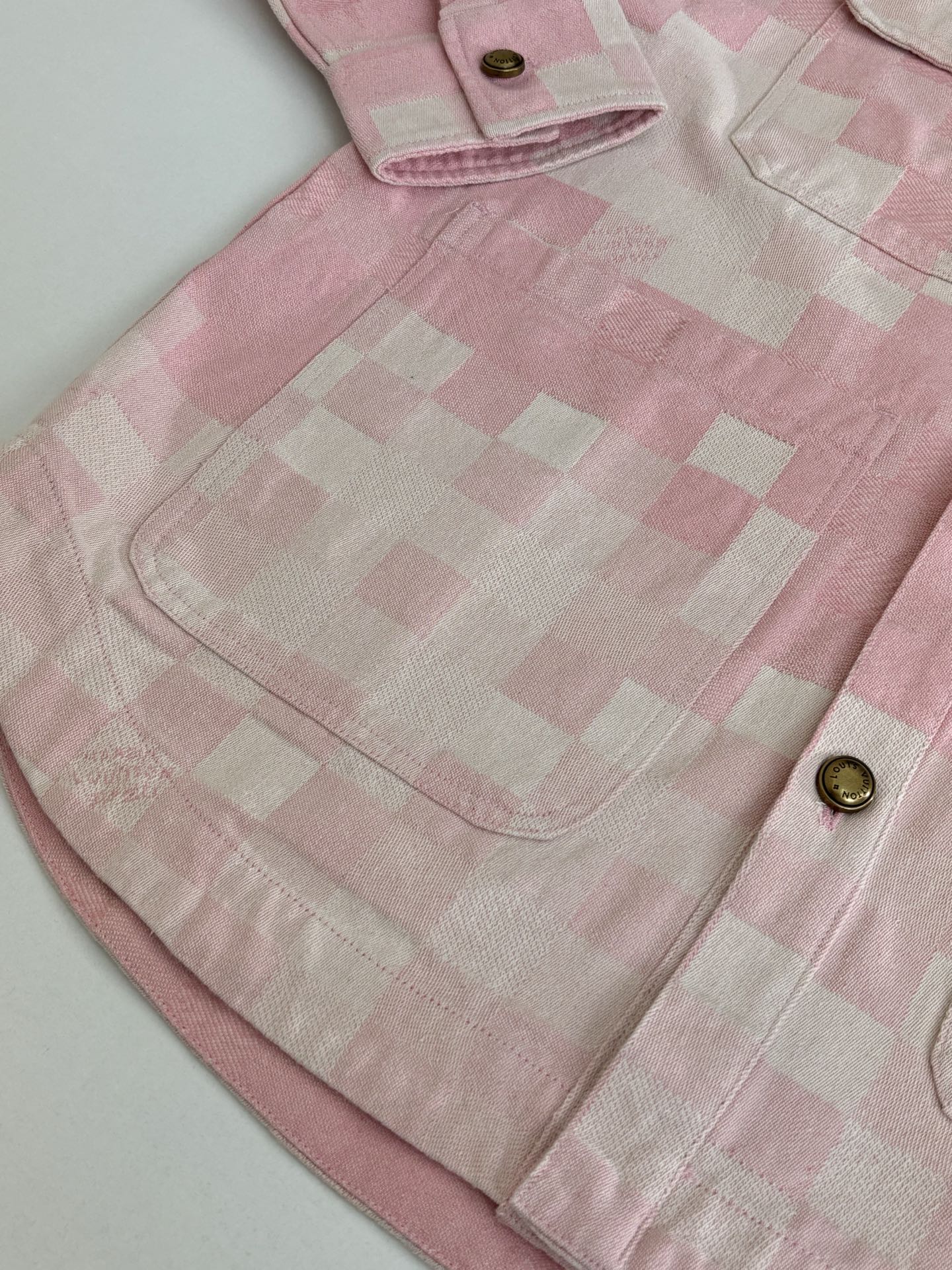 Pink hooded jacket yoke area with check pattern, top button, and front pocket