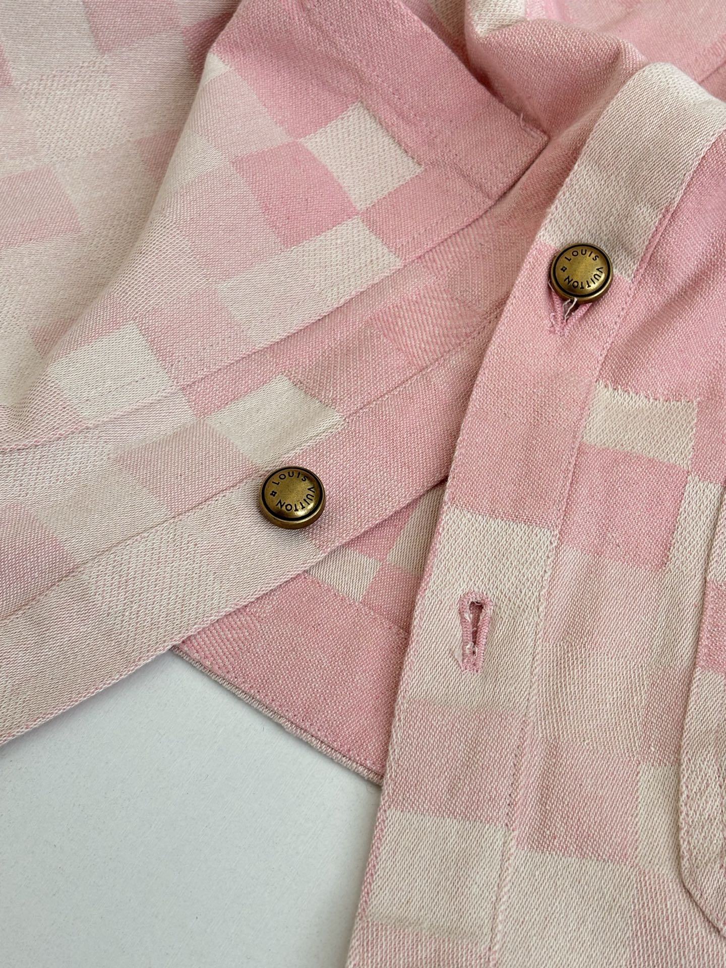 Pink hooded jacket shoulder and chest detail with gold buttons and check pattern