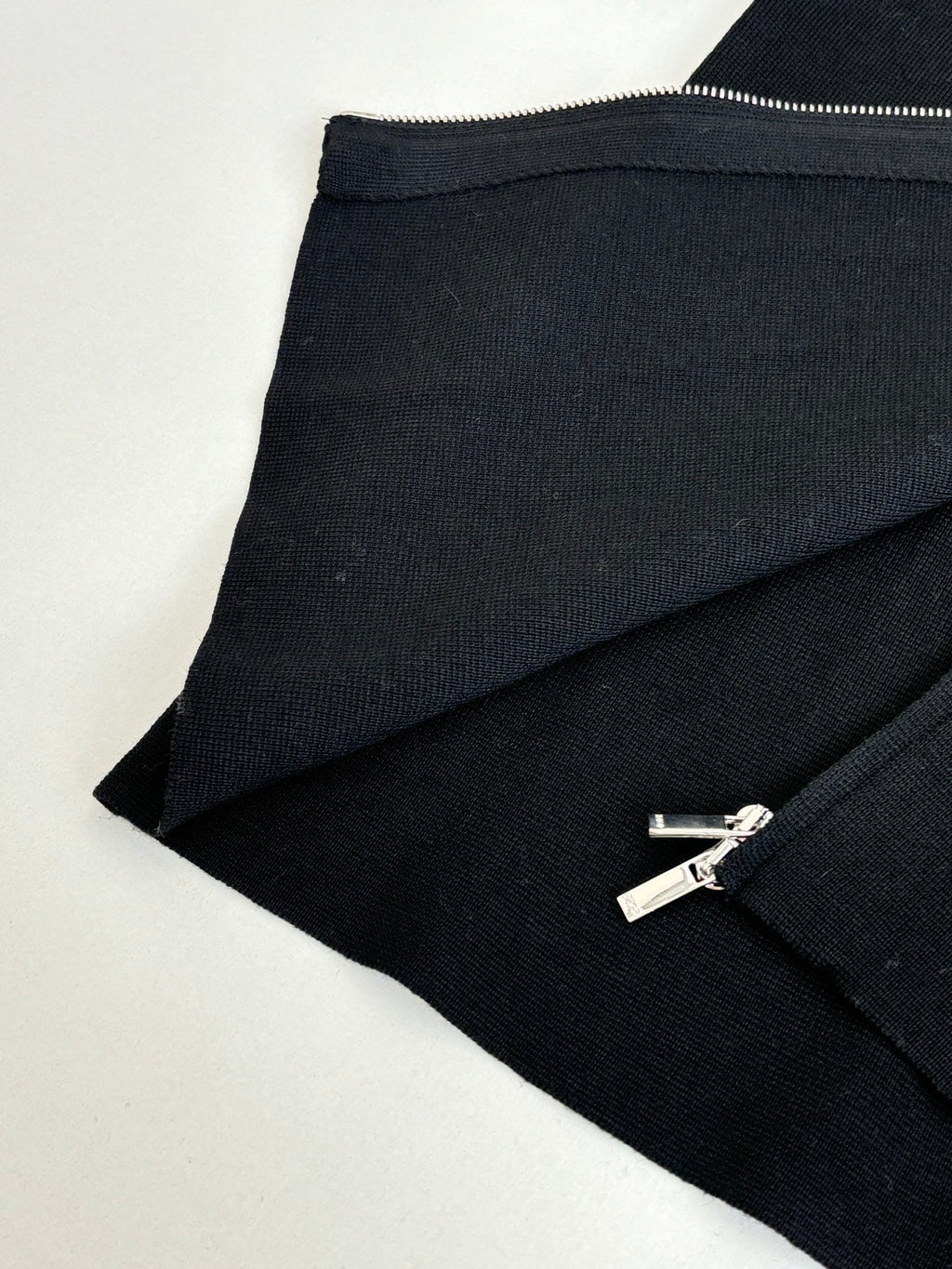 Black zip jacket hem and zipper with silver pull, angled close-up