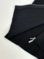 Black zip jacket hem and zipper with silver pull, angled close-up