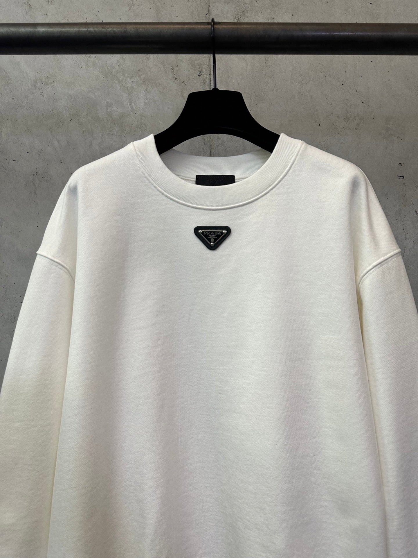 White sweatshirt neckline with embroidered Prada triangle logo patch