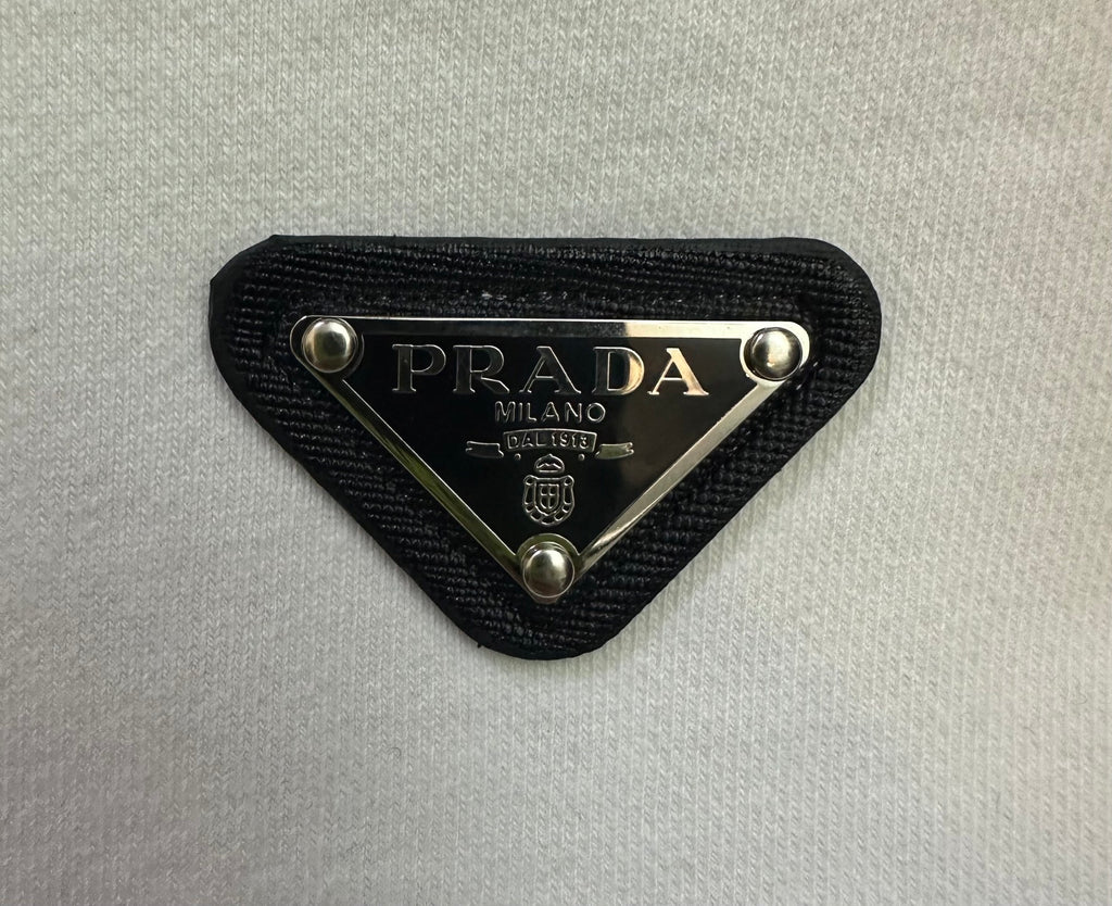 Black fabric PRADA logo patch with gold-trimmed triangle hardware