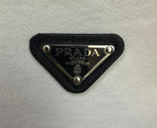 Black fabric PRADA logo patch with gold-trimmed triangle hardware