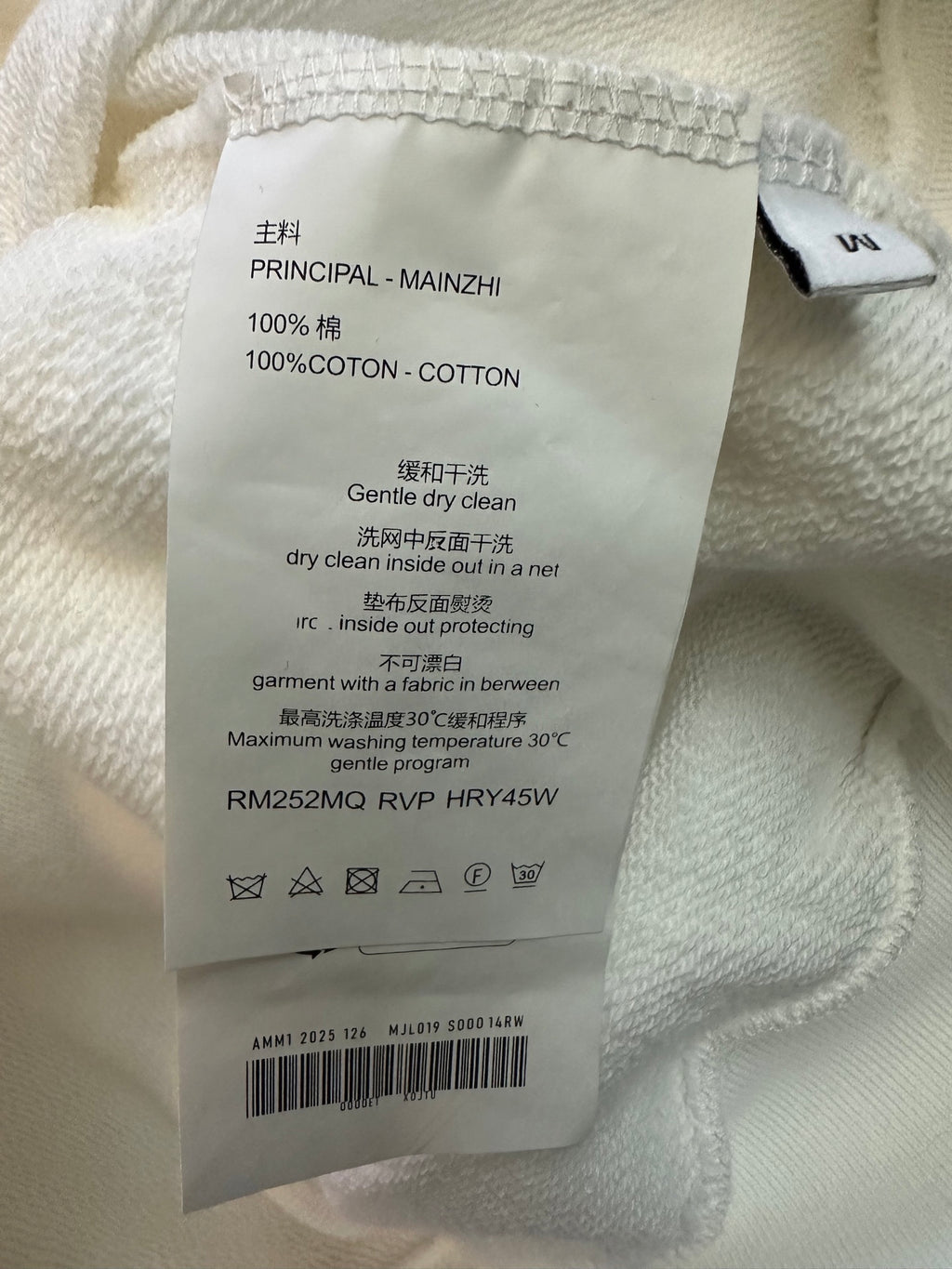 Clothing care label inside white sweatshirt: 100% cotton, dry clean
