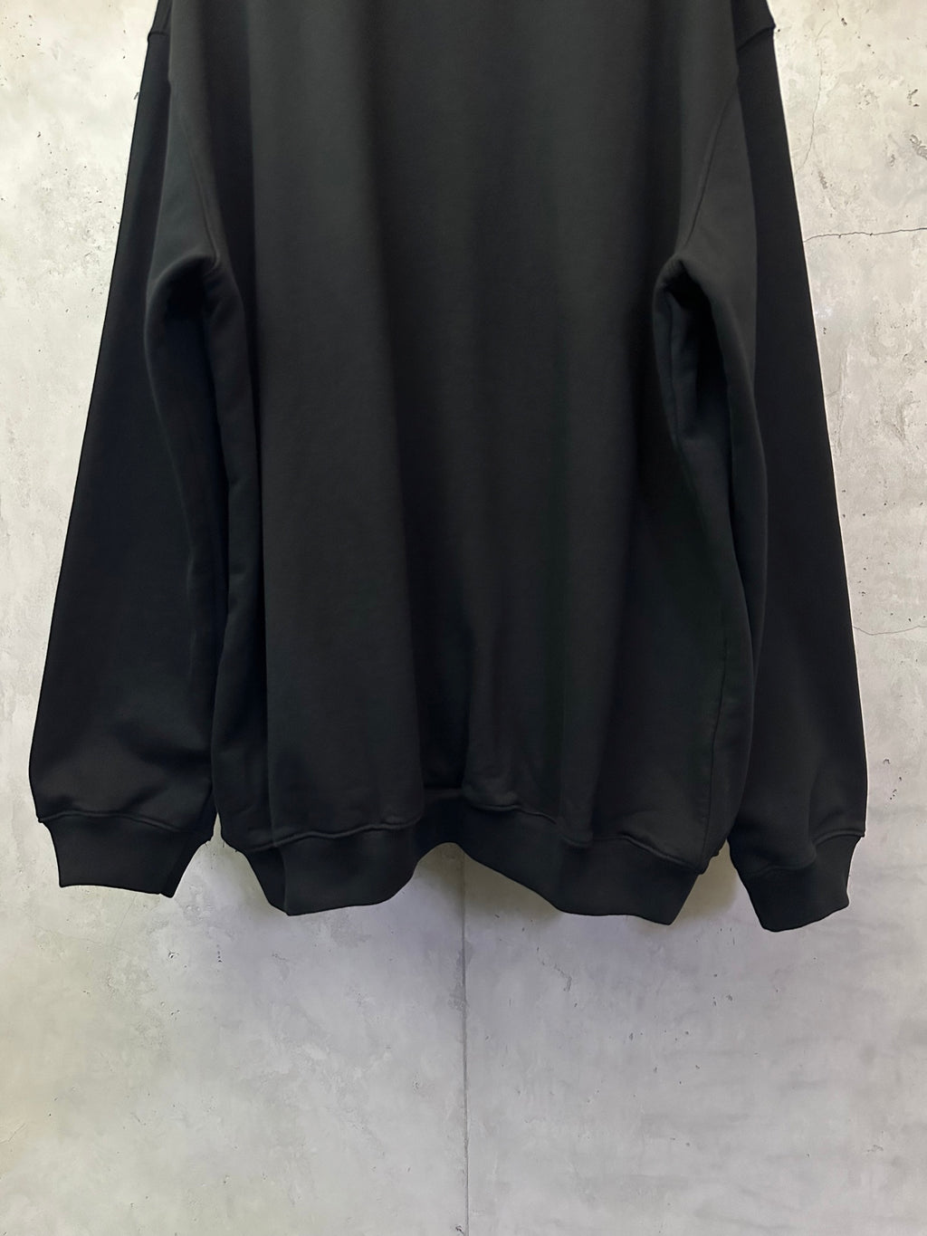 Black sweatshirt back view with ribbed cuffs and rounded hem