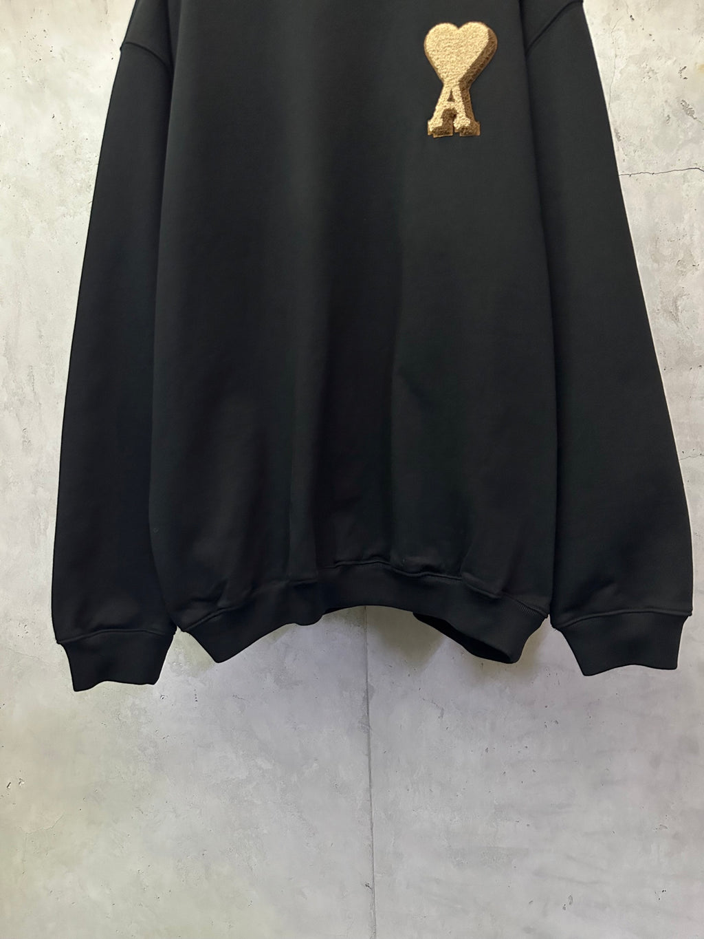 Black sweatshirt with gold A heart logo near the upper chest, long sleeves and ribbed hem