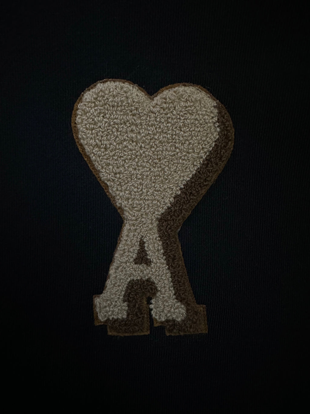 Gold heart and A logo patch on black sweatshirt fabric