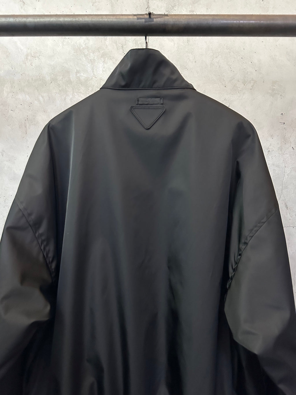 Black back bomber jacket with triangular PRADA patch at the collar