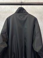 Black back bomber jacket with triangular PRADA patch at the collar