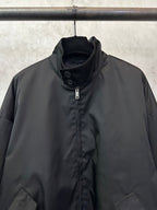 Black stand-collar jacket with center zip and snapped placket detail