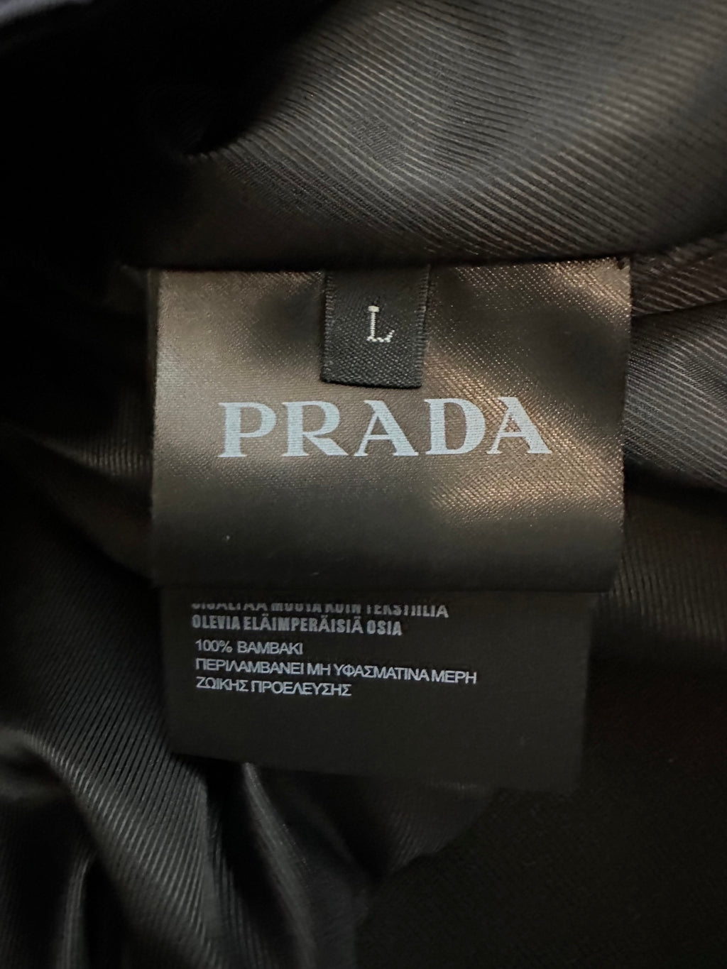 Interior PRADA size label marked “L” on black jacket lining