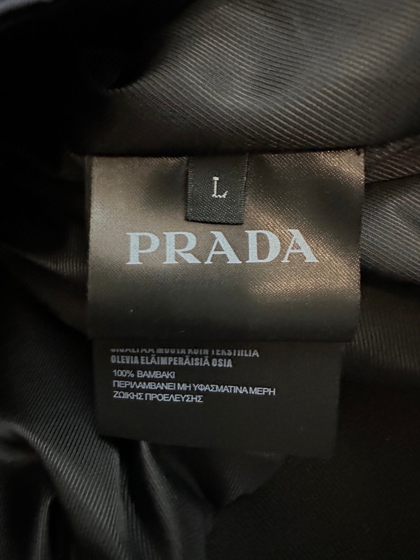 Interior PRADA size label marked “L” on black jacket lining